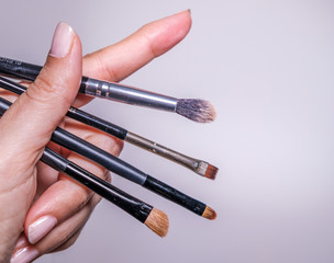 makeup equipment. Professional brushes. Color sample hands holding tools. Lip, shadows,blending, broncer tools