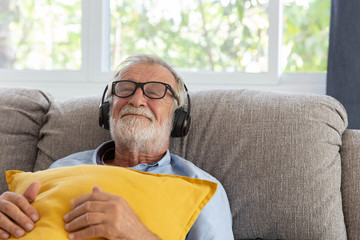 Wall Mural - Senior retirement man listen to music using headphone feeling happy in his home