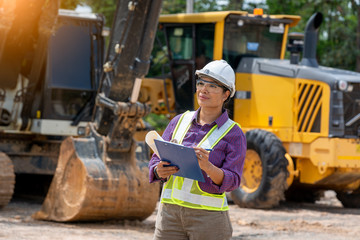 Female engineer worker on construction site outdoors with excavator in background,construction Site,construction machinery, bulldozer, excavation.