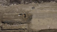 Top Down Aerial Shot Of Heavy Equipment Working On A Dirty Construction Job Site. Excavator Loading Rock Trucks.