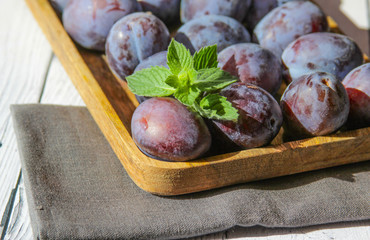 Fresh and sweet plum with leaves on the wooden background.