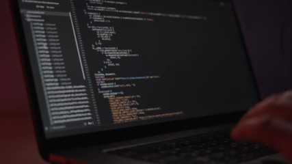 Software computer programming code, typing in laptop. Close up of screen with programming code, working programmer typing on black screen