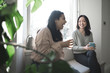 © CarlosGLopez - A British-Bangladeshi woman and an Asian woman chat and laugh while having a cup of sitting next to a window as the sun comes through in a flat in Edinburgh, Scotland, United Kingdom