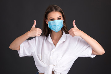 young woman with medical face mask, expressing emotions isolated on dark background