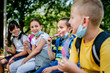 © Ana - Group of children eating ice cream  outside. They are wearing a protective face mask down.