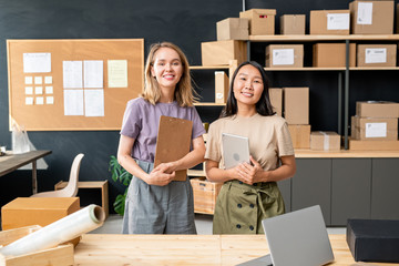 Sticker - Two young cheerful female workers of online shop office standing by table