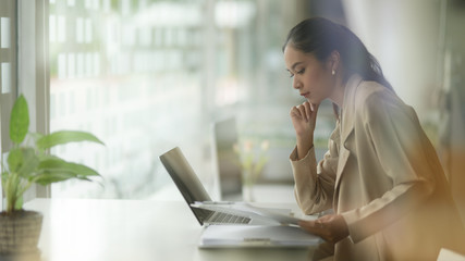 View through glass window of female concentrating on her work on office desk