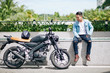 © DragonImages - Proud Vietnamese biker sitting on parapet and looking at his motorcycle