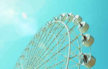 Ferris Wheel under the clear blue sky was rolling at Huis ten bosch theme park at Nagasaki, Japan. Vintage tone with flares.