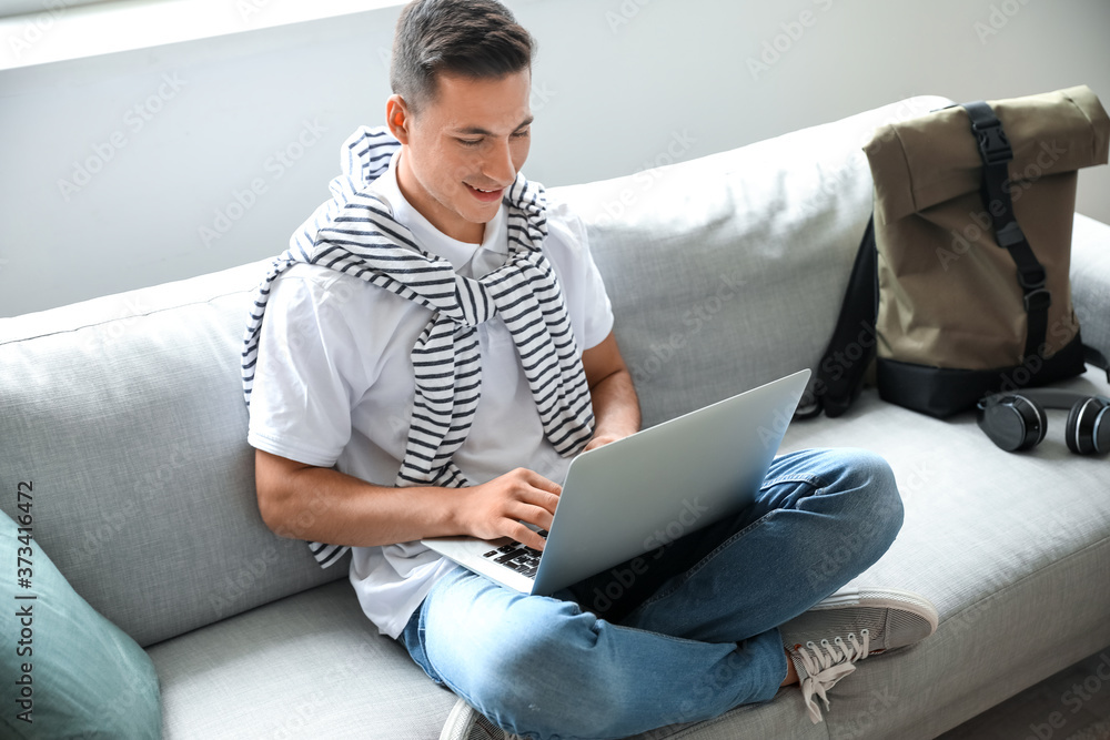 Man with laptop booking tickets online at home