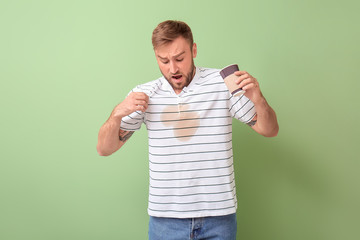 Sticker - Stressed young man with coffee stains on his t-shirt on color background