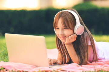 Canvas Print - Little girl with laptop listening to music in park