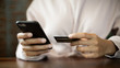 © EduLife Photos - Close up of a teenage woman holding credit card and smart phone make online payment. Stock photo.