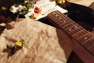 Still life with an electric guitar, dried flowers and old music notes close up.