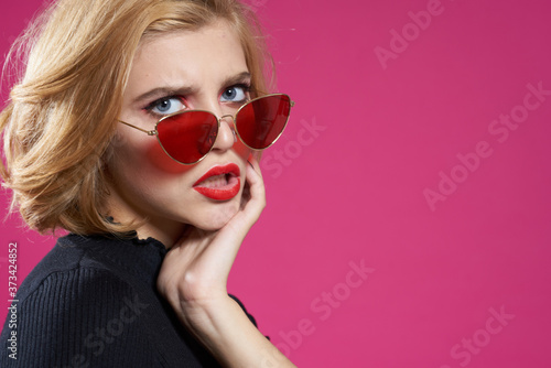 Cuadros en Lienzo Pretty woman in dark glasses bright makeup black jacket close-up pink background