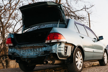 A car without a bumper, the exhaust pipe is visible. The boot lid is open. Auto after an emergency. Repair is needed. Car insurance concept