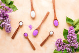 Fototapeta  - Pattern of spa sea salt in spoons with lilac flowers. Above view