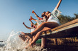 © Zoran Zeremski - Group of young friends sitting on the edge of a pier having fun and enjoying a summer day at the lake.