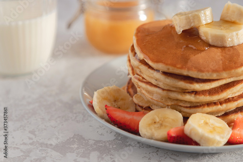 Close-up on a stack of pancake with banana and strawberry, drizzled with sweet syrup Tableau sur Toile