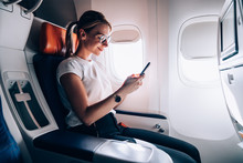 Happy Relaxed Woman Using Smartphone In Contemporary Aircraft