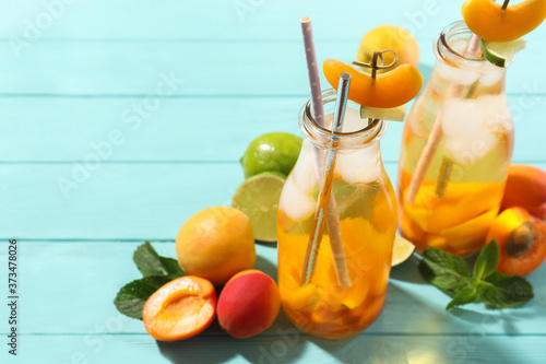 Delicious refreshing drink with apricot on light blue wooden table. Space for text
