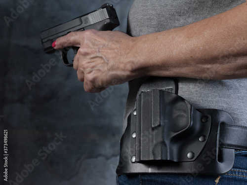 Photographie Women's hand holstering a gun close up