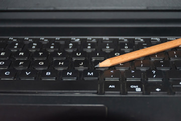 A pencil placed on a laptop computer keyboard