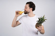 © Ivan - Man with long beard holds pineapple in hands and drink the juice from it. Dieting and fitness. Look at camera