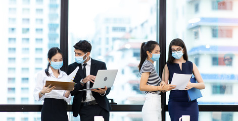 Young businesswoman and business man wearing protective face mask while meeting for making new business plans during COVID-19 pandemic