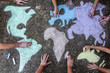 © JoseLuis - A group of people drawing with colored chalks on the floor with his hands in the street a map of the world