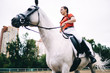 Focused horsewoman riding grey horse in paddock