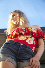 Sticker - Low angle shot of a beautiful blonde female wearing an off shoulder blouse and shorts