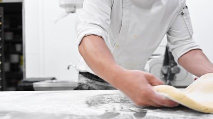 Wall Mural - Chef kneading dough at commercial kitchen. Pastry Chef hands kneading dough on the table at pastry shop. High quality FullHD footage