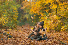 Two Children Throwing Autumn Leaves In The Air