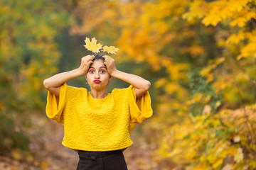 Cheerful woman portrait with autumn maple leaves in the park