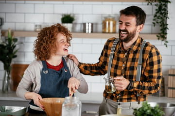 Wall Mural - Boyfriend and girlfriend making delicious food at home. Loving couple cooking in kitchen..