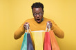 © Viktor Koldunov - Shocked african young man holding shopping bags being surprises.