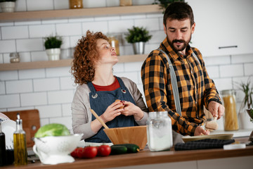 Wall Mural - Boyfriend and girlfriend making delicious food at home. Loving couple cooking in kitchen..