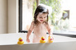 © Lisa Tichané - Smiling toddler girl playing with rubber ducks in bathtub