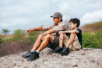 Wall Mural - Latin grandfather with his grandson enjoying the natural landscape. Concept of grandparents and grandchildren in outdoor activity