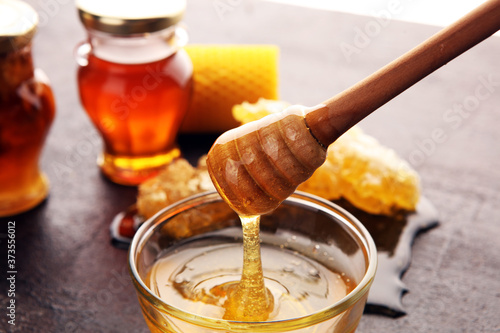 Photographie Honey in jar with honey dipper on vintage rustic background