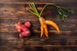 Trendy ugly organic carrot with the halm and potato from home garden on on a wooden background, unnormal vegetable or food waste concept, copy space