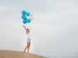 © Irina Magrelo - Young woman holding blue and white helium balloons