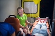 © Anna Kosolapova - Sad girl looking at the woman lying on a stretcher in an ambulance car, the girl is holding her sister's hand.