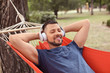 © Pixel-Shot - Handsome man listening to music while relaxing in hammock outdoors