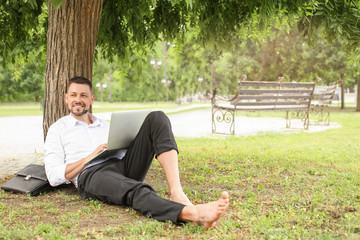 Sticker - Handsome businessman with laptop relaxing in park