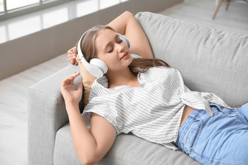 Sleepy young woman listening to music at home