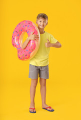 Poster - Cute little boy with inflatable ring showing thumb-up on color background