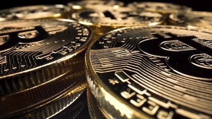 Wide-angle macro view golden bitcoins turning round on reflective glass surface, black background, cryptocurrency investment 4k