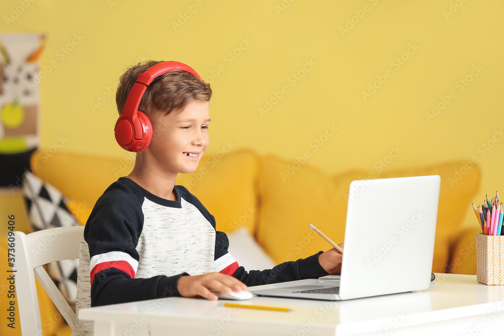 Little boy with headphones using laptop at home